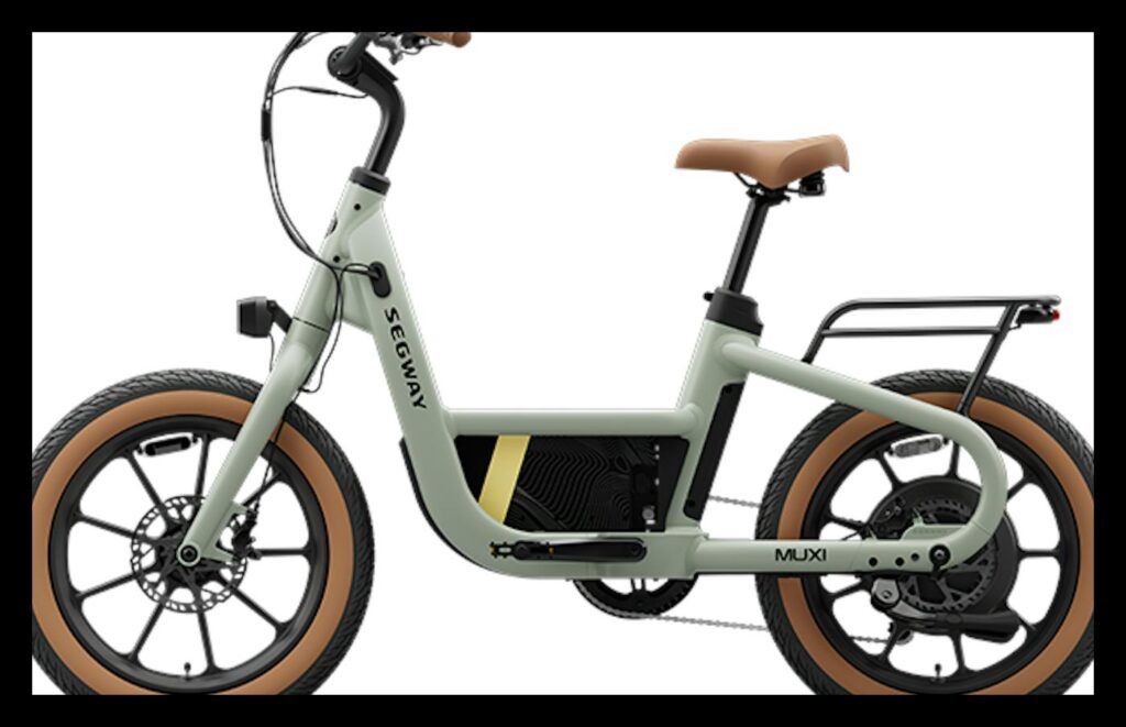 Segway Muxi compact electric bike in pale sage green, left-side profile on a white background, showing its small 16-inch wheels with tan sidewall fat tires, brown saddle and grips, low step-through frame, disc brake and rear cargo rack.