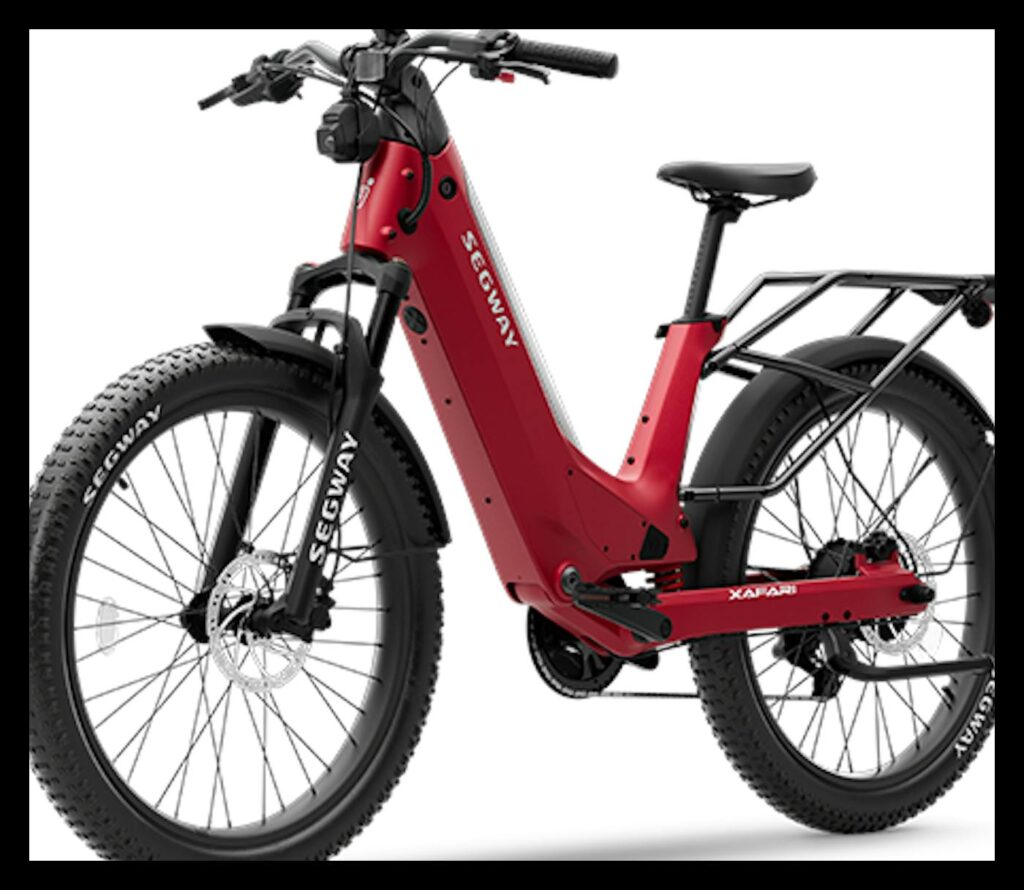 Segway Xafari electric bike in red, three-quarter front view on a white background, showing its step-through frame with integrated battery, front suspension fork, fenders, wide knobby 26-inch style tires with Segway lettering, and a black rear cargo rack.