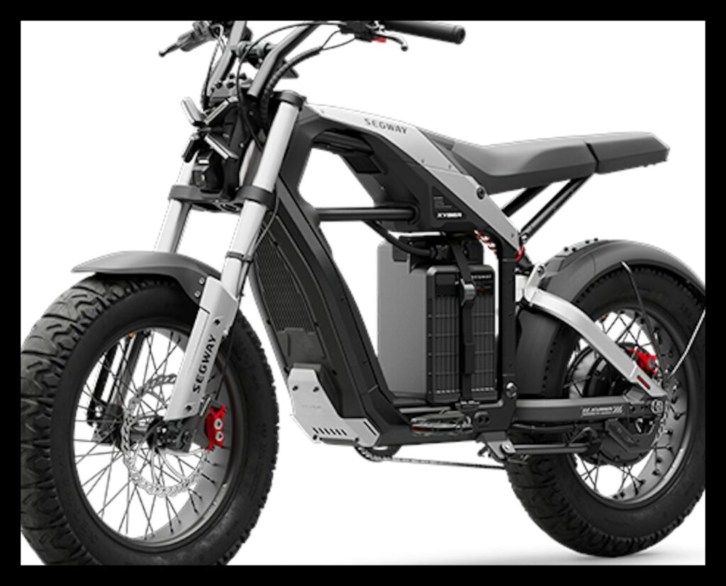 Segway Xyber electric off-road e-bike in silver and black, three-quarter front view on a white background, showing its open cast-aluminum frame with exposed removable battery pack, 20-inch fat knobby tires on spoked wheels, red brake calipers, upside-down front fork and flat motorcycle-style seat.